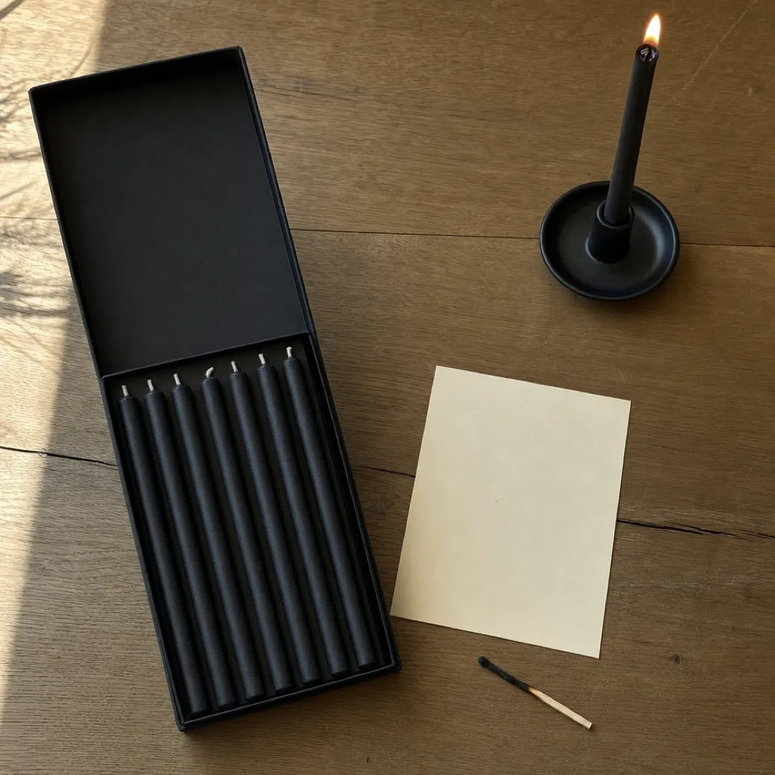 Das geöffnete Set mit sieben schwarzen Kerzen, daneben die Karte